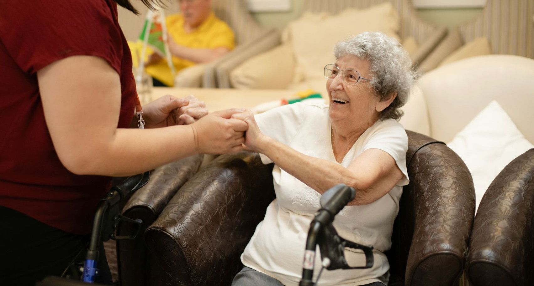 Caregiver assists elderly woman with walker.